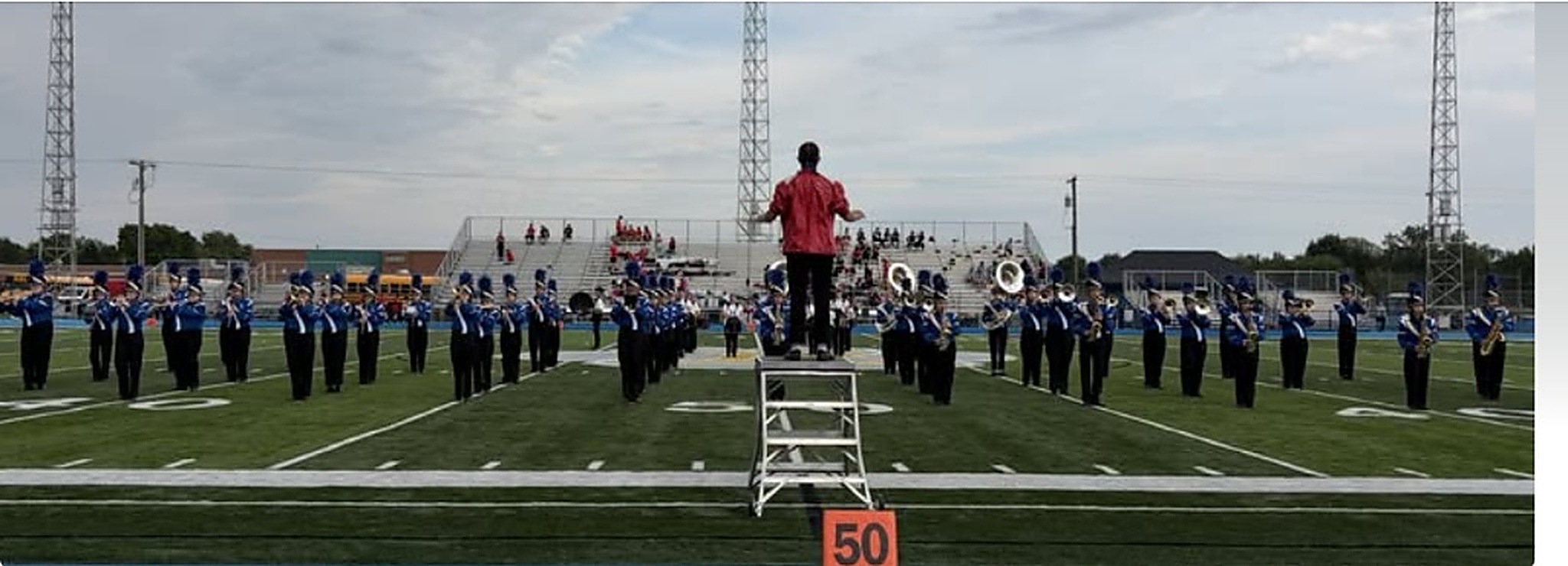 Lincolnview Marching Band performing on turf football field in Royal Blue and White uniforms facing bleachers